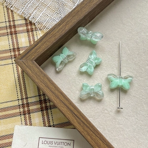 Macro shot of mint green and clear butterfly glass beads on rustic linen for jewelry DIY