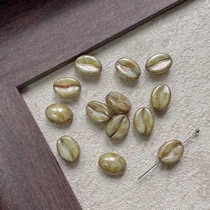 Detailed close-up of coffee bean shaped glass beads showing gradient olive color and hole