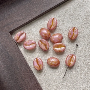 Macro shot of coffee bean shaped beads with purple gradient and through-hole detail