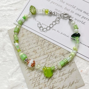 Handmade green glass bead bracelet featuring floral ceramic bead and leaf charms