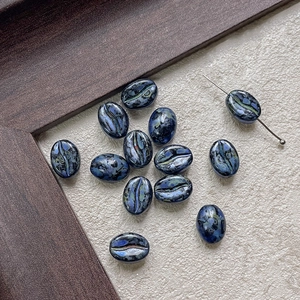Macro shot of dark blue coffee bean shaped glass beads with metallic sand texture and DIY hole