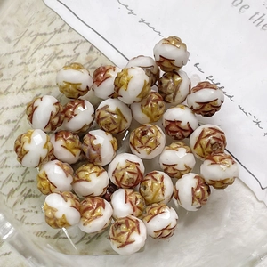 Macro shot of faceted white glass beads with vintage brown hand-painted rose patterns