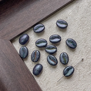 Detailed view of metallic purple coffee bean beads for DIY jewelry with threading needle