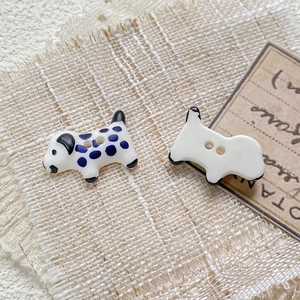Detail of hand-painted ceramic dalmatian dog shaped beads with dual holes for DIY jewelry
