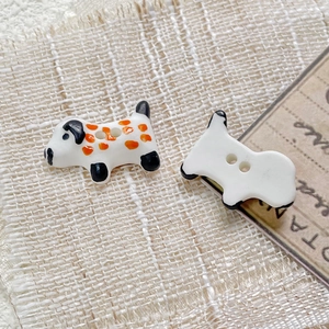 Macro shot of hand-painted ceramic dalmatian-shaped buttons with orange spots for DIY sewing