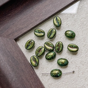 Macro shot of coffee bean shaped glass beads with antique bronze and gold textured finish