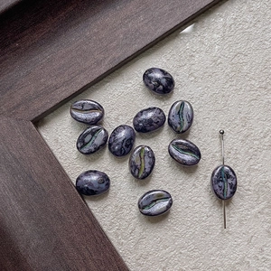 Macro shot of coffee bean glass beads with marble texture and needle for jewelry making