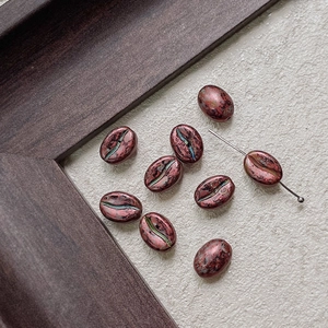 Macro shot of bronze coffee bean beads with vintage patina and metal threading needle