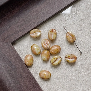 Detail of coffee bean shaped glass beads with realistic spotted texture for DIY jewelry