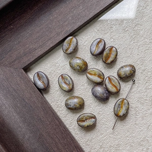 Macro shot of coffee bean shaped Czech glass beads with vintage marbled glaze for DIY crafts