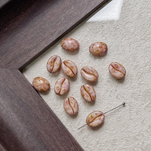 Macro detail of coffee bean shaped glass beads in dusty pink for DIY jewelry making