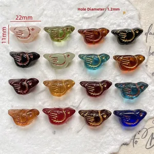 Detailed view of bird-shaped glass beads with gold etched feather textures and 1.2mm holes