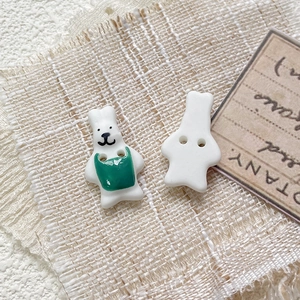 Detail of handmade ceramic rabbit button with green hand-painted apron and two-hole design