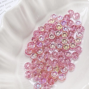 Detailed view of pink daisy glass beads for DIY jewelry making in a white shell tray