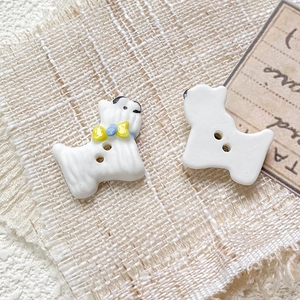 Close-up of hand-painted white ceramic dog bead with yellow bow for DIY jewelry making