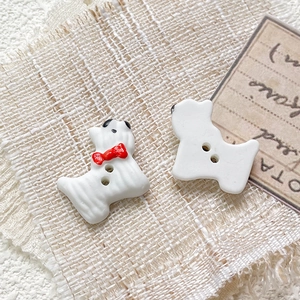 Macro detail of two hand-painted ceramic dog beads for DIY jewelry with two-hole design