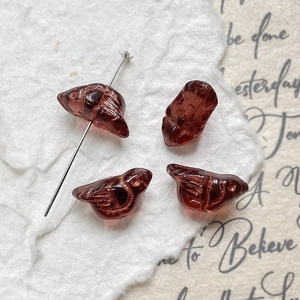 Macro detail of bird-shaped red glass beads with gold etched lines for DIY jewelry
