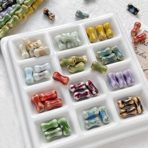 Assorted colorful ceramic bone-shaped beads for DIY jewelry making in a white tray