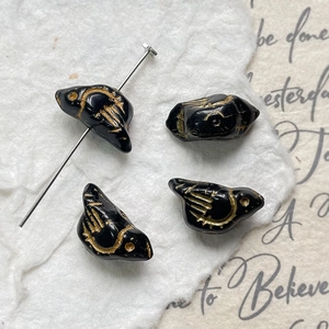 Macro detail of four vintage bird-shaped beads with gold feather etching for DIY jewelry