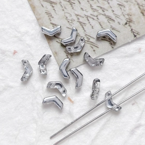 Macro detail of silver V-shaped two-hole Czech glass beads for DIY jewelry making