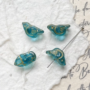 Detail of vintage blue glass bird beads with golden hand-painted accents for jewelry DIY