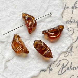 Detail of amber bird beads with gold feather etching for DIY jewelry making