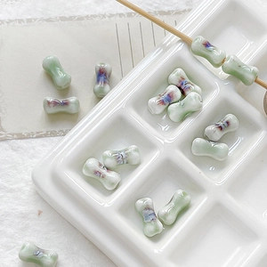 Detail of bone-shaped ceramic beads with green and purple glaze for DIY jewelry