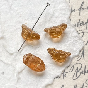 Macro detail of amber bird glass beads with gold wing texture for DIY jewelry making