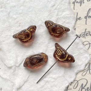 Macro shot of bird-shaped glass beads with gold painted wings for DIY jewelry