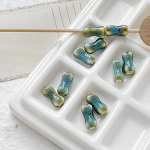 Detailed view of bone-shaped ceramic beads with a reactive glaze finish for DIY jewelry