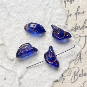 Detail of dark blue bird glass beads with bronze engraving for DIY jewelry making