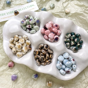 Assortiment keramische kralen met bloemen- en schelpatronen in een wit bakje