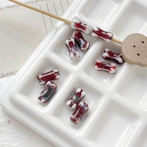 Macro detail of bone-shaped ceramic beads with red splash glaze for DIY jewelry