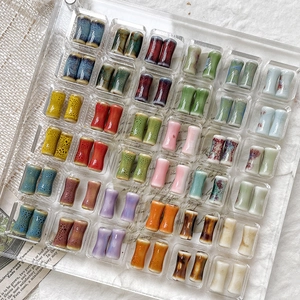 Colorful bamboo-shaped ceramic beads for DIY jewelry displayed on a grid tray