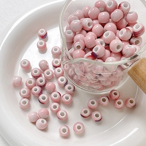 Close-up of pink glazed ceramic beads with wide holes for DIY jewelry making