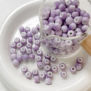 Macro detail of glossy purple ceramic beads with center holes for DIY jewelry making