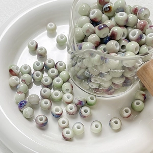 Macro detail of round celadon ceramic beads with colorful glaze in a glass cup