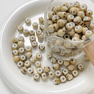 Macro detail of cream ceramic beads with brown leopard spots in a clear measuring cup