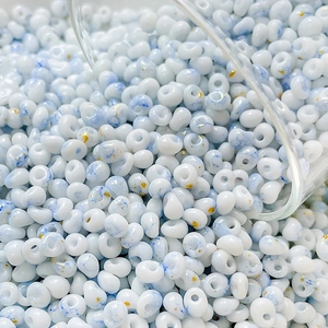 Macro detail of 4mm blue and white marble glass seed beads with gold glitter accents