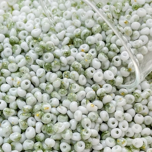 Macro shot of 4mm cream beads with green fog texture and gold foil flakes for DIY jewelry