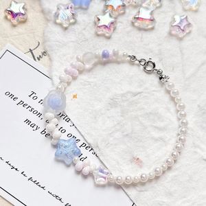 Dreamy handmade beaded bracelet with blue star and floral charms on white paper