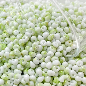 Macro detail of 4mm cream glass beads with green marble texture and gold speckles for DIY