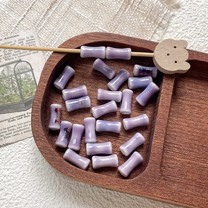 Detailed view of hand-painted purple bamboo-shaped ceramic beads on a rustic wooden tray