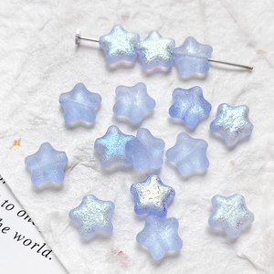 Detail of matte light blue star-shaped glass beads with iridescent AB coating for DIY crafts