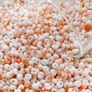Macro detail of 4mm cream glass beads with orange marble texture and gold foil flakes