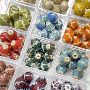 Dettaglio di perle in ceramica sfaccettate con smalto screziato in una scatola chiara