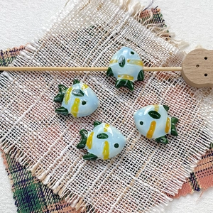 Close-up of hand-painted blue ceramic tropical fish beads for DIY jewelry making