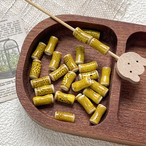 Detail shot of hand-painted bamboo joint ceramic beads in yellow glaze on wooden tray