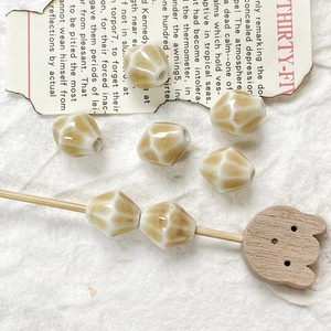 Dettaglio di perline di ceramica crema con finitura a crepe per gioielli fai-da-te