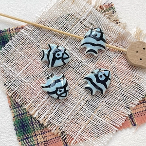 Detailed view of four handmade ceramic tropical fish beads for DIY jewelry making